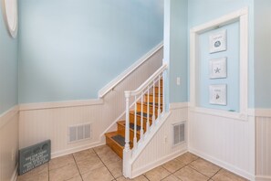 A staircase with white railings and wooden steps, leading to a landing with a vented wall.