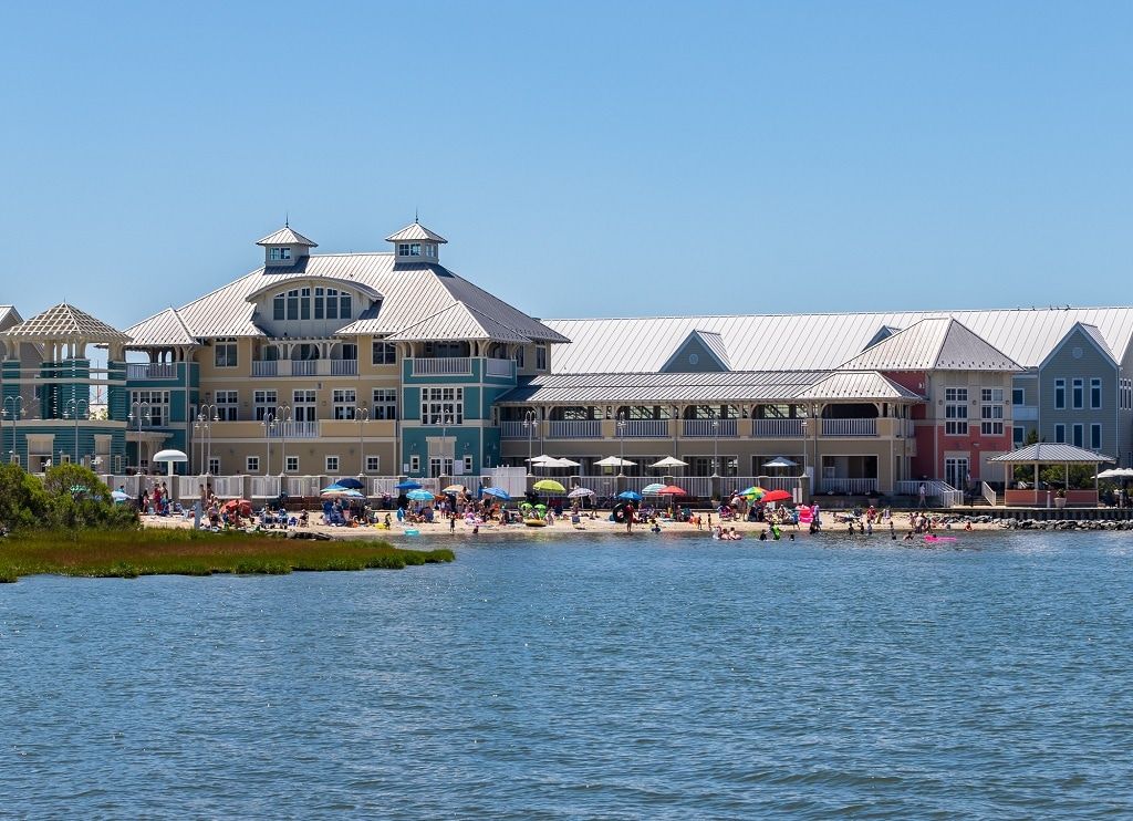 A waterfront hotel with multiple buildings, a beach, and umbrellas.