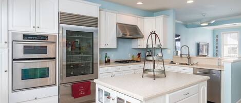 Una cocina moderna con armarios blancos, electrodomésticos de acero inoxidable y una isla central.