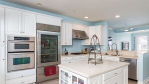 A modern kitchen with white cabinetry, stainless steel appliances, and a central island.
