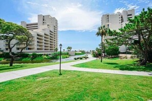Un complejo de apartamentos moderno con varios edificios altos, un césped cuidado y un cielo despejado.