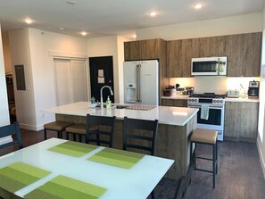 A modern kitchen with a central island, white cabinetry, and stainless steel appliances.