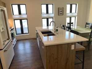 A modern kitchen with a central island, wooden cabinets, and a dining area with a table and chairs.
