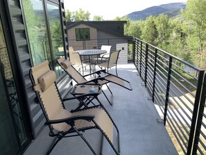 A balcony with outdoor seating, a table, and a view of the surrounding landscape. - An all-seasons condo on the Blue River in Silverthorne, CO. (Silverthorne)