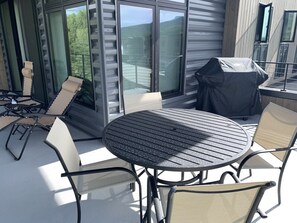 Une terrasse extérieure avec une table ronde et des chaises, un barbecue et une vue sur les environs.