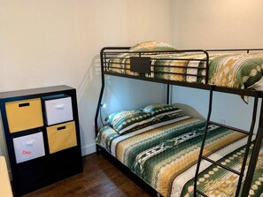 A bunk bed with a patterned bedspread and pillows, a black metal headboard, and a storage unit with labeled compartments. - An all-seasons condo on the Blue River in Silverthorne, CO. (Silverthorne)