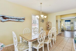 A dining area with a table and chairs, a chandelier, and a decorative piece on the wall.