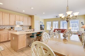 A spacious kitchen with a large island, wooden cabinets, and a dining area with a chandelier.