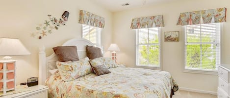 A bedroom with a bed, bedside lamps, a nightstand, a dresser, and a ceiling fan.