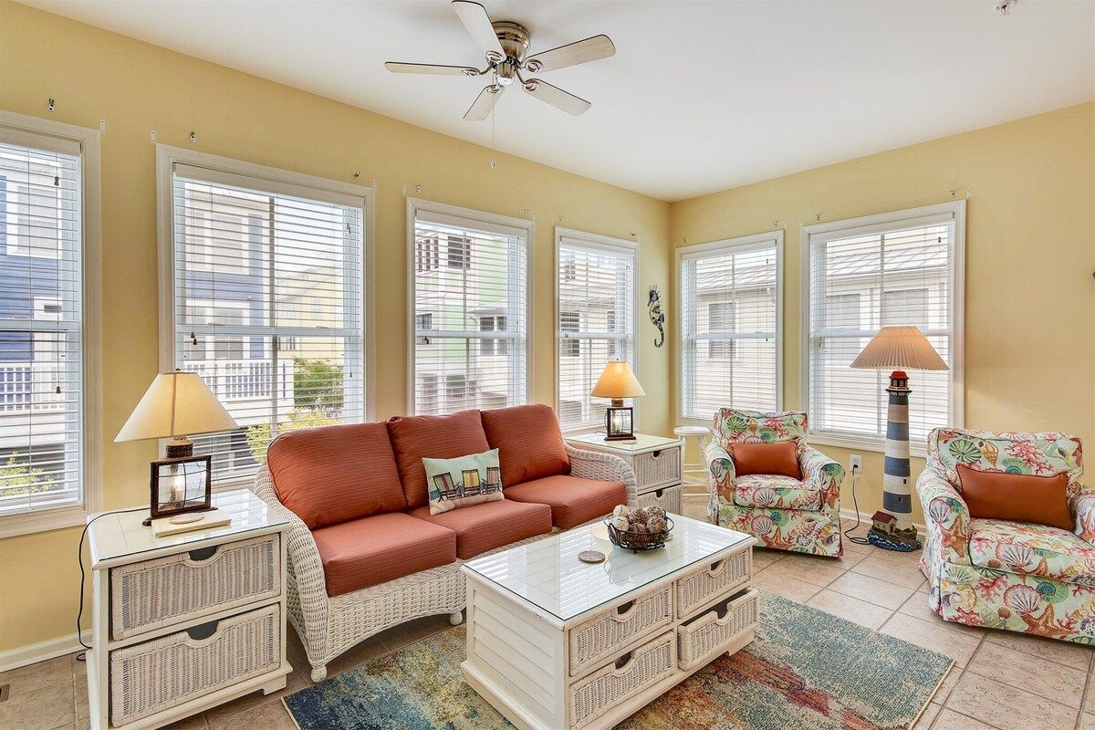 A living room with a sofa, armchairs, a coffee table, and a ceiling fan.