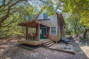 A wooden cabin with a porch, a deck, and a grill area. - 1214 - Toad Hall - Cozy Corolla Cottage | Walk to Beach & Village (Corolla)