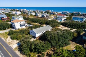 A coastal residential area with houses, a road, and a beach in the background.