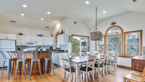 A spacious kitchen with a central island, white cabinetry, and a dining area with a wooden table and chairs. - 1559 - Sound Retreat - Spacious Corolla Soundfront w/ Sunset Views & Pool (Corolla)