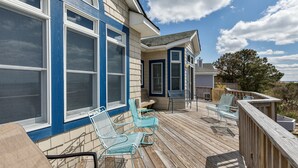 A wooden deck with outdoor seating, a covered patio area, and a view of the surrounding landscape. - 1559 - Sound Retreat - Spacious Corolla Soundfront w/ Sunset Views & Pool (Corolla)