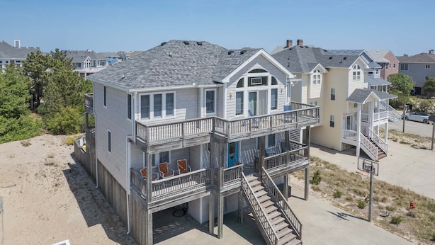 A beachfront house with a balcony, a staircase, and a view of the beach. - 1618 - Dune Buggy - Walk to Beach | Private Pool & Hot Tub (Corolla)