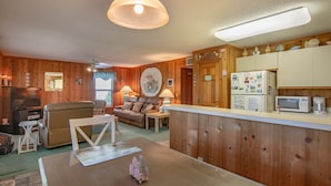 Ein gemütliches Wohnzimmer mit einer Couch, einem Esstisch und einer Küchenzeile inklusive Kühlschrank und Mikrowelle.