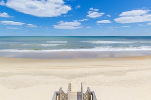 A beach with a wooden walkway leading to the water.