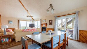 Ein gemütliches Wohnzimmer mit Kamin, einem Essbereich mit Holzsesseln, einem Fernseher und einem Bücherregal.