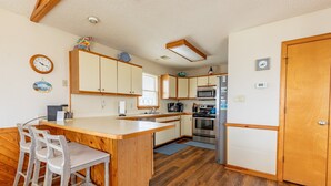 Eine kompakte Küche mit Holzausbau, einer zentralen Kochinsel mit Barhocker, einer Mikrowelle und einem Kühlschrank.