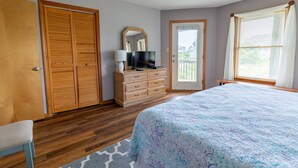 Ein Schlafzimmer mit Bett, Holzschrank, Kommode und Fernseher.