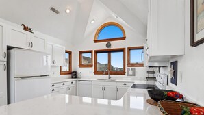 Een moderne keuken met witte kasten, een groot eiland en een dakraam.