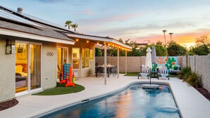 A backyard with a swimming pool, patio furniture, and a 'Quit Office' sign. - Designer 4BR w/ Free Heated Pool & Fire Pit,  Hiking Trail Right Off the Yard (Scottsdale)