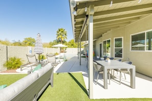 An outdoor patio with a pool, seating, and a covered dining area.
