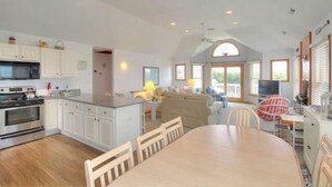 Una cocina amplia con armarios blancos, una isla grande y un comedor con mesa y sillas redondas.