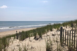 Une plage avec des dunes de sable et une clôture en bois.