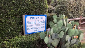 Señal que indica un área privada llamada 'Sound Beach' solo para propietarios e invitados de 'Caffey's Inlet Hamlet'.