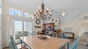 A dining area with a wooden table and chairs, a chandelier, and a view of the kitchen and living area. - 2820 - Dabbling Duck - Spacious Duck Getaway | Pool, Hot Tub & More (Duck)