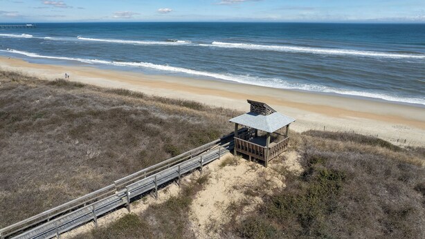 Une plage dotée d’une structure en bois et d’une promenade qui y mène.