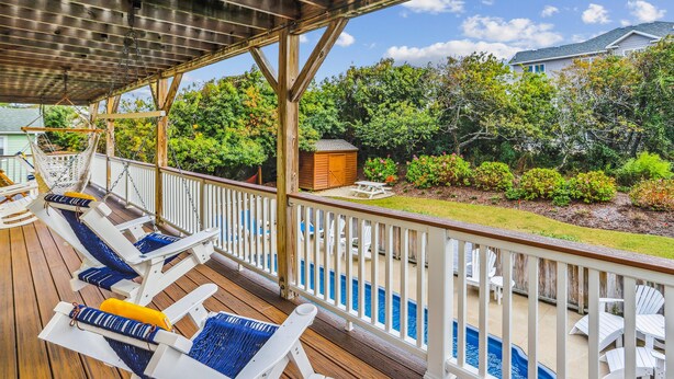 Une terrasse couverte avec des chaises longues et une piscine.