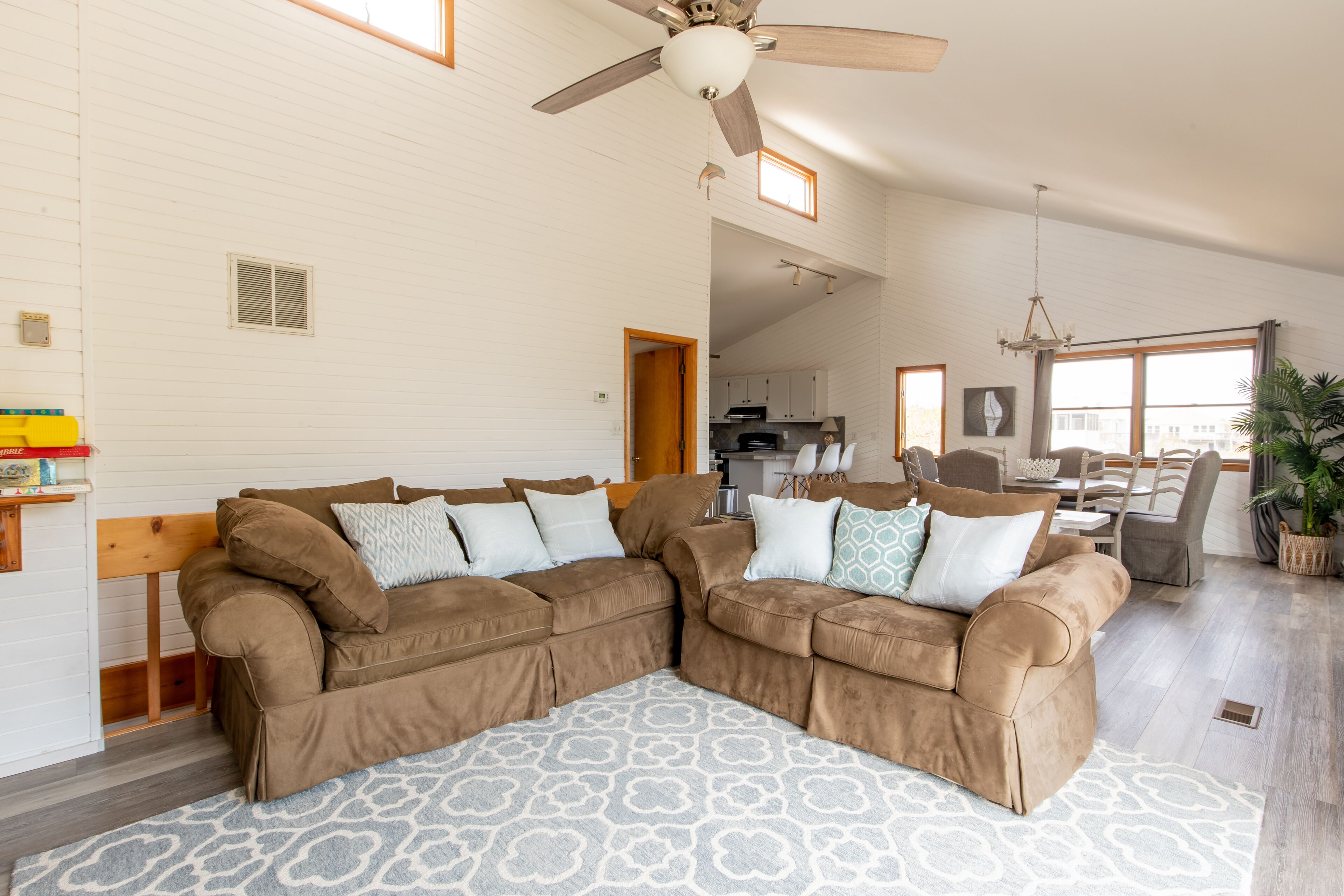 A spacious living room with a large brown sectional sofa, a patterned rug, and a ceiling fan.