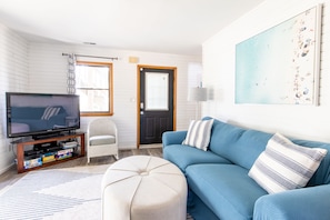 A living room with a television, a sofa, a chair, and a rug.
