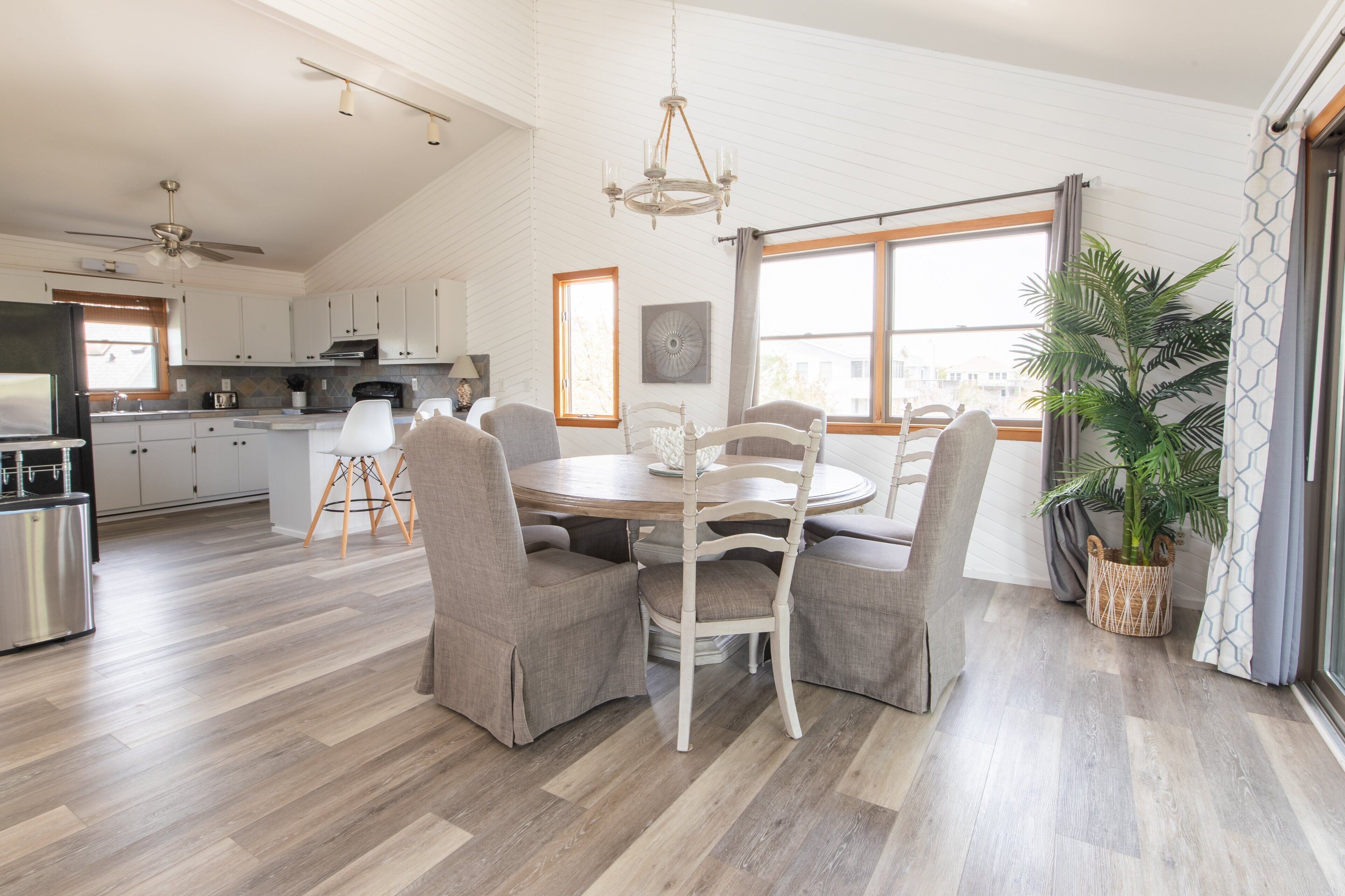 A spacious kitchen with modern appliances, a dining area with a round table and chairs, and a large window providing natural light.