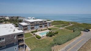 A multi-story residential building with a swimming pool, a parking area, and a view of the ocean. - 4104 - Sever's Hideaway, Cozy Coastal Retreat | Walkable Duck Location (Duck)