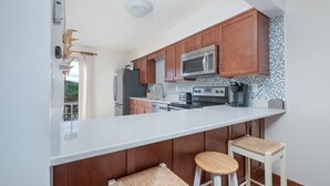 Una cocina moderna con armarios de madera, una isla grande con taburetes, un microondas y un refrigerador.