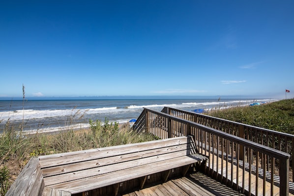 A wooden boardwalk leading to a beach with waves crashing onto the shore.