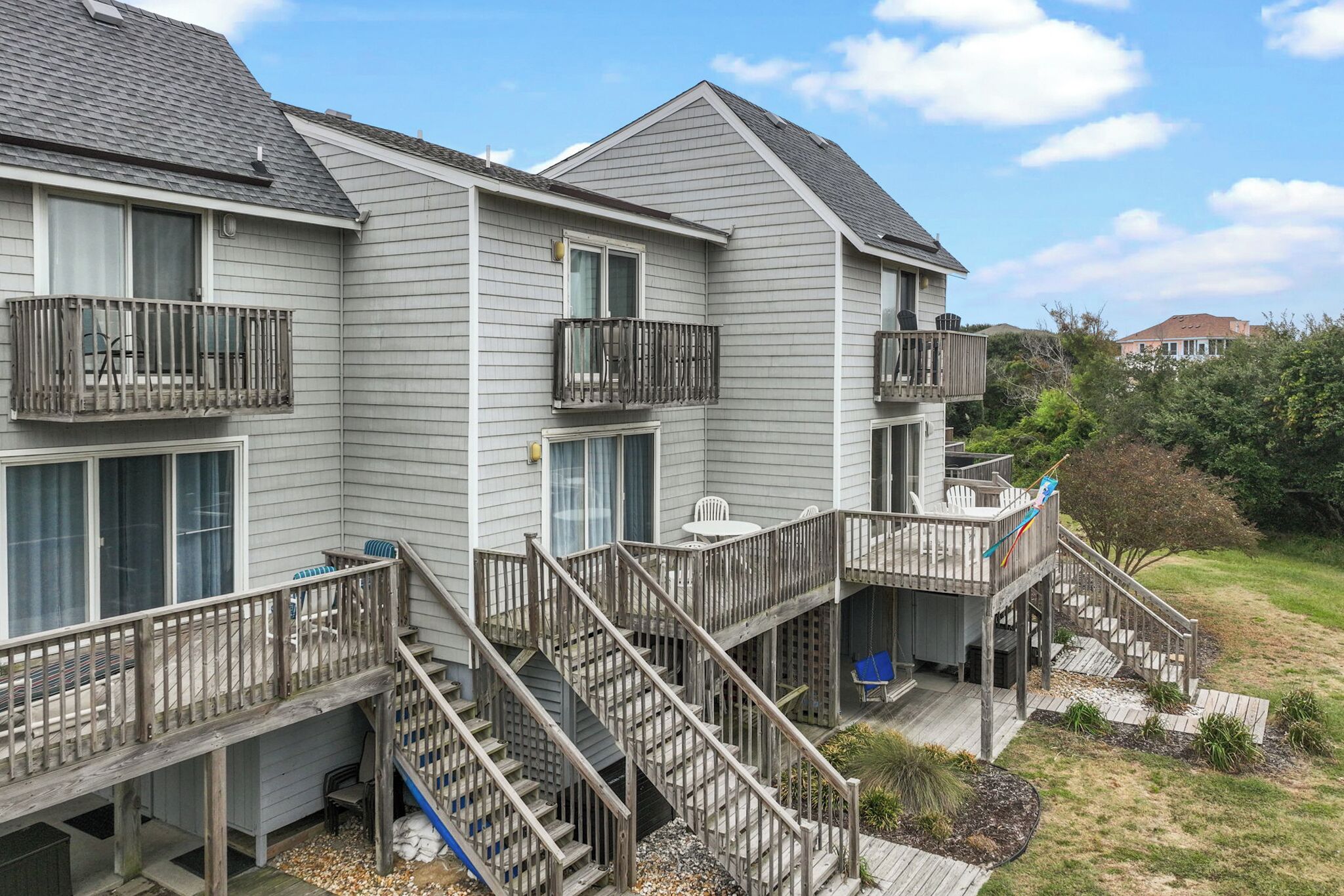 A two-story residential building with a covered deck and a staircase.