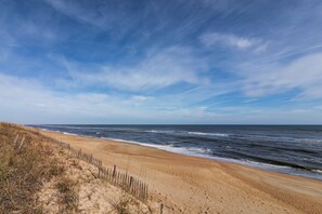 A beach with a wooden fence and sandy dunes.