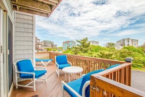 A covered outdoor deck with blue chairs and a table, overlooking a residential area. - 4220- Timeless, 33 Yards to Beach | Ocean Views in Duck (Duck)