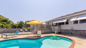 A backyard with a swimming pool, a wooden deck, and a covered patio area. - 4601-Sandy Bluff - Southern Shores Home w/ Private Pool (Southern Shores)