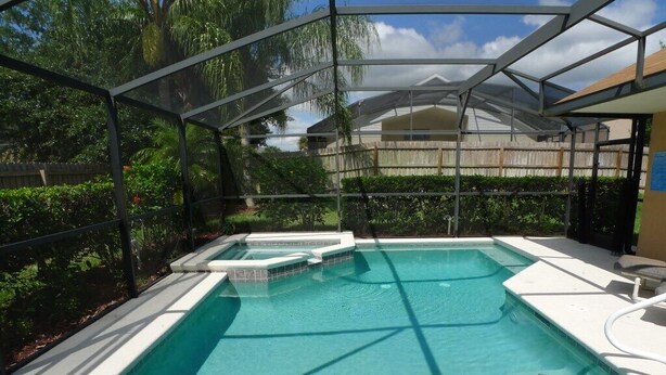 Une piscine dotée d’un espace couvert, entourée d’une végétation luxuriante et d’une clôture en bois.