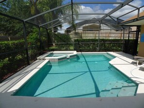 A swimming pool with a covered area, surrounded by lush greenery and a wooden fence. - Orange Tree Home w/ Pool & Spa, 15 mi to Disney (Clermont)