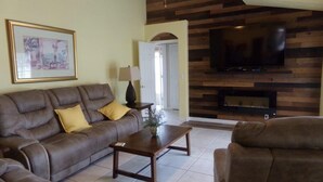 Un salon comprenant un canapé, une table basse, un téléviseur fixé au mur, qui est en bois, et un tableau encadré accroché au mur.
