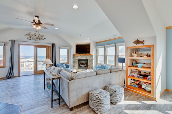 A spacious living room with a large sofa, a fireplace, and a bookshelf.