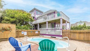 A two-story house with a pool and deck chairs. - 4751- Purple Passion - Walk to Beach | Pool, Hot Tub & Dogs Welcome (Kitty Hawk)
