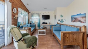 Un salón acogedor con paredes de madera, un televisor y un comedor con mesa y sillas.
