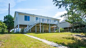 A two-story house with a covered porch and a staircase leading to the upper floor. - 5002 - Bohannon - Soundfront KDH Escape w/ Sunset Views (Kill Devil Hills)